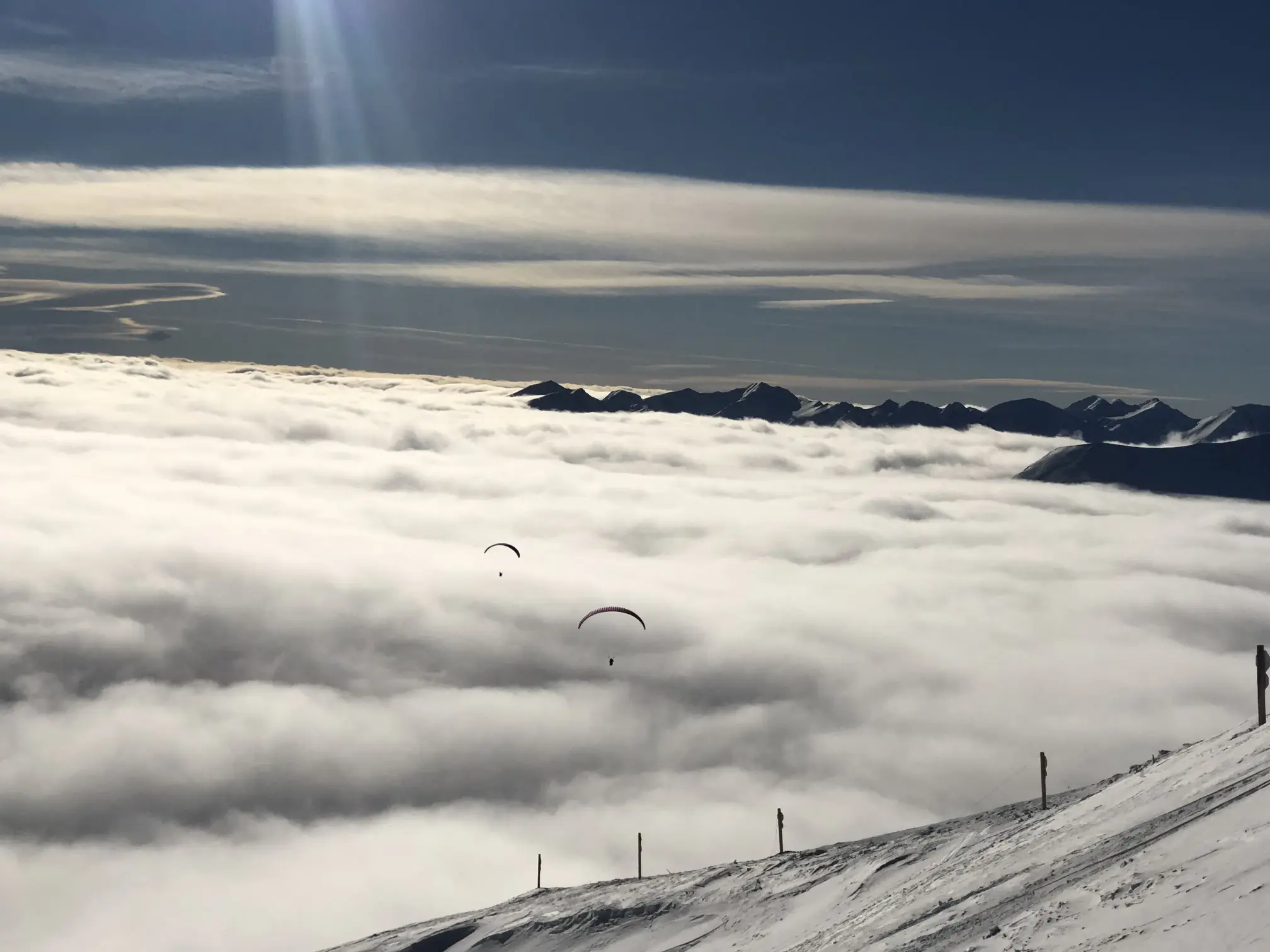 Tandem paraglider taking off from a snowy launch site in Gudauri