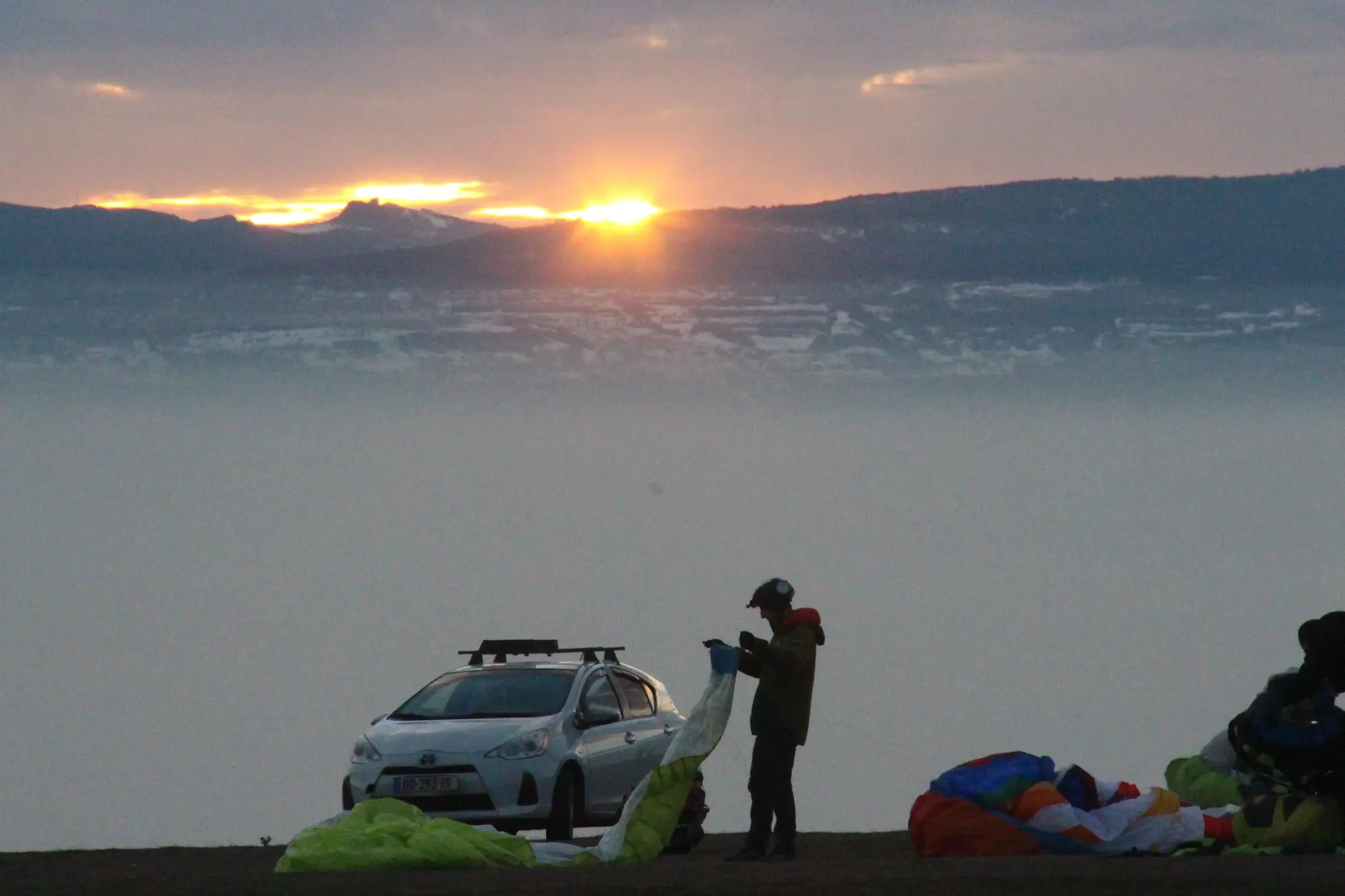 Paraglider silhouette at sunset over the Caucasus ridges